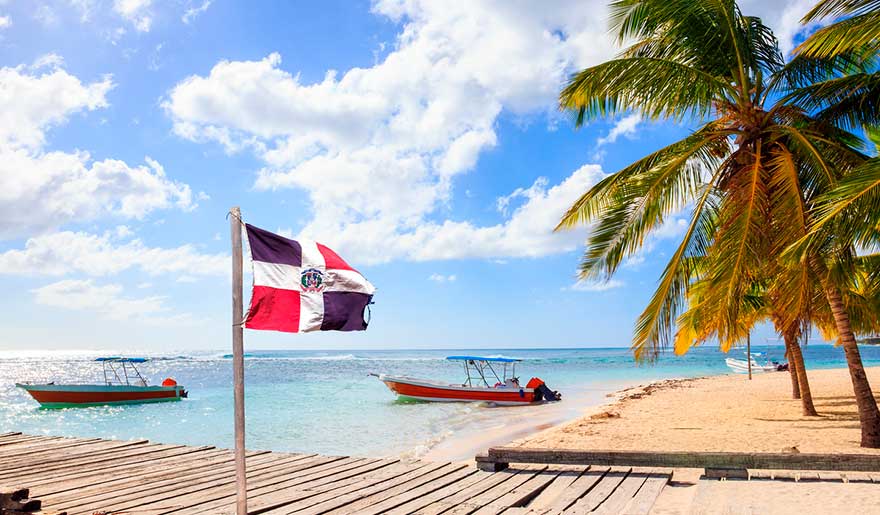 Flag waving in front of some boats on the shore of the beach in the Dominican Republic Flag waving in front of some boats on the shore of the beach in the Dominican Republic