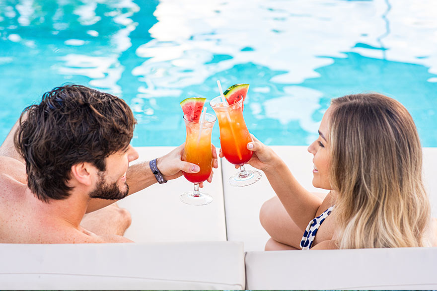 Pareja brindando con cóctel en la piscina